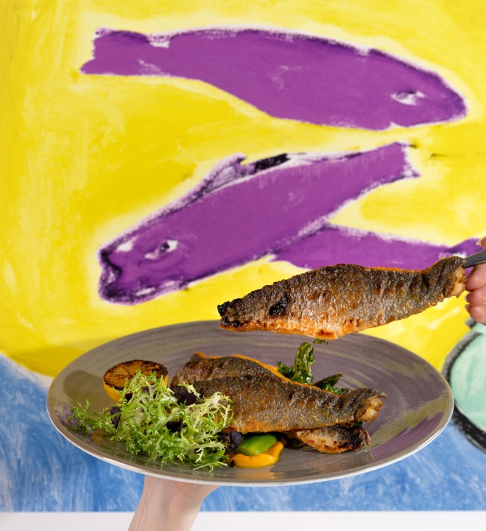 Plato de pescado con un colorido mural de peces de fondo