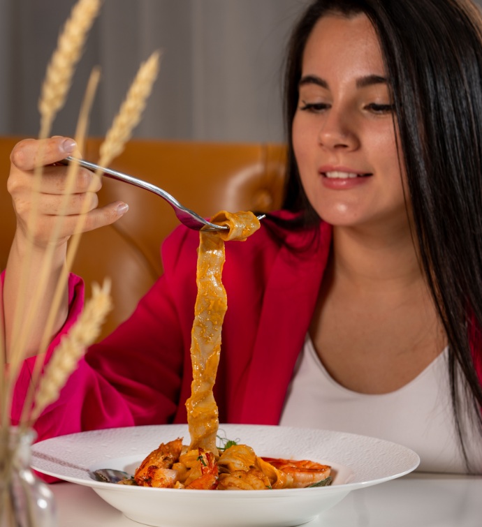 Femme vêtue d'un blazer rouge mangeant une pizza