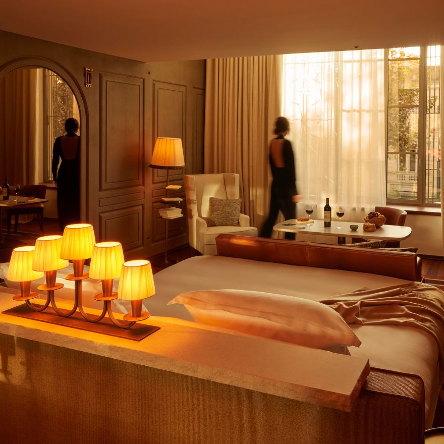 Person in a large dimly-lit hotel suite looking out of floor-to-ceiling windows