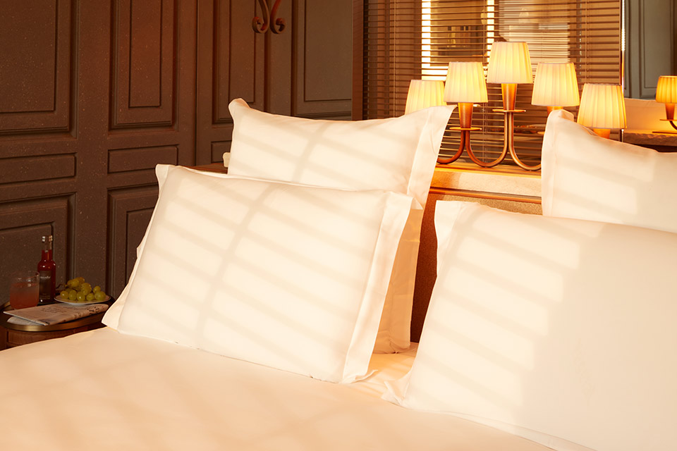 A neatly made bed with white sheets and pillows.