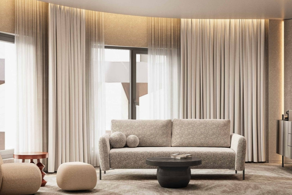 Modern hotel room with beige interiors and sofa, pouf, with windows behind it