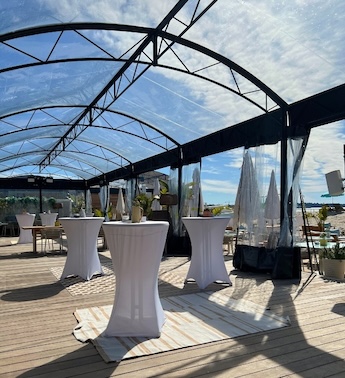 Patio extérieur avec tables de bar rondes recouvertes de nappes et parasols blancs