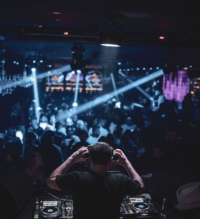 DJ at a DJ booth with a crowd of people in Black Orchid nightclub