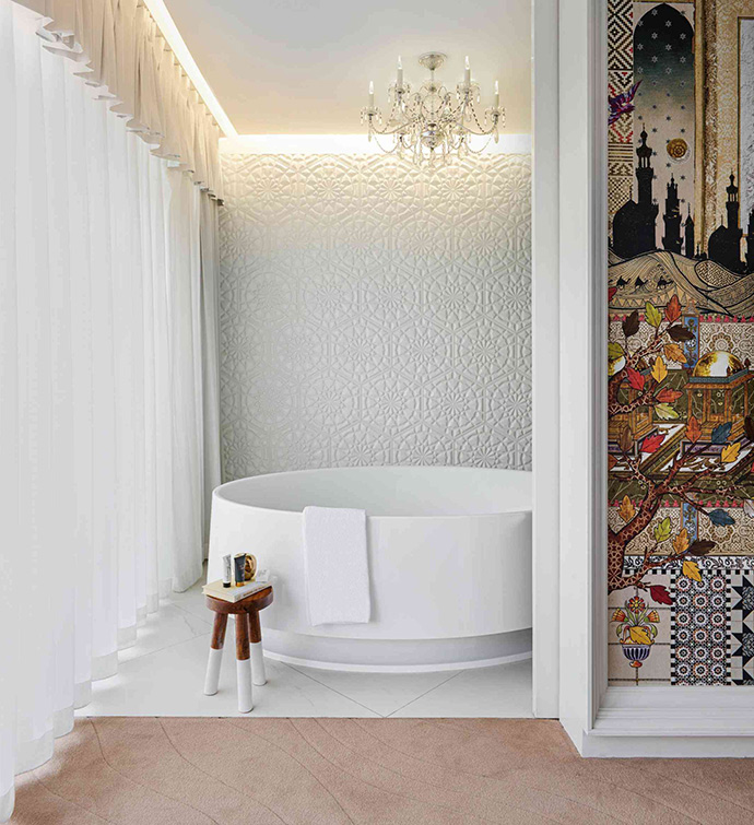 Salle de bain avec une baignoire blanche et un mur orné de carreaux brillants.