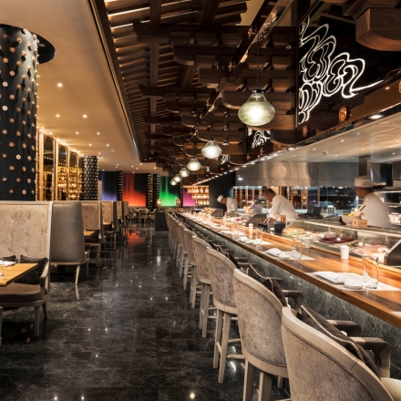 Interior de Morimoto Doha con una larga barra y chefs de sushi