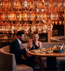 Lustre géant composé de lanternes au-dessus d'un couple dégustant des sushi au Morimoto Doha