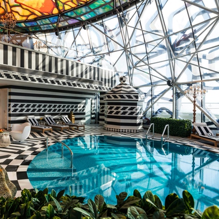 Piscine ronde du spa Mondrian Doha avec un sol et des murs noirs et blancs, ainsi qu'un plafond en vitrail.