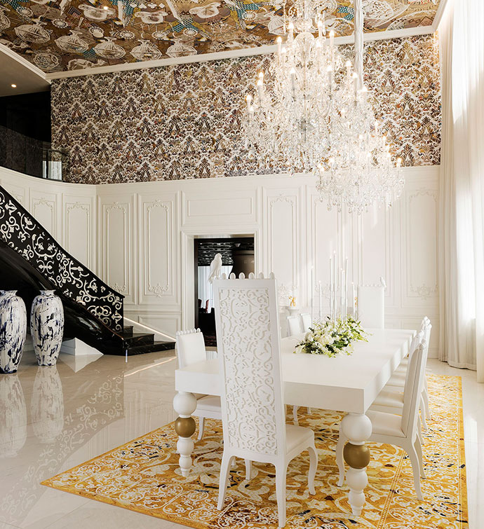 A luxurious dining room with a sparkling chandelier hanging above a staircase.