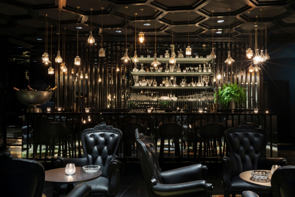 Intérieur du Smoke and Mirrors Doha avec des sièges en cuir noir et un bar long 