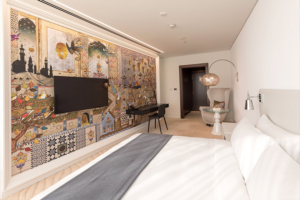 Chambre d’hôtel avec une peinture murale colorée.