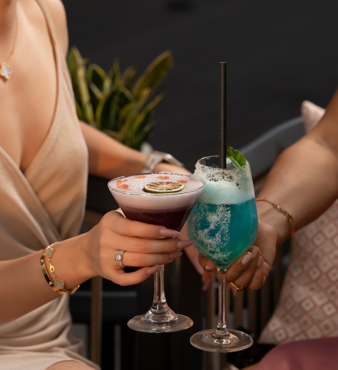 Two ladies holding purple and blue cocktails