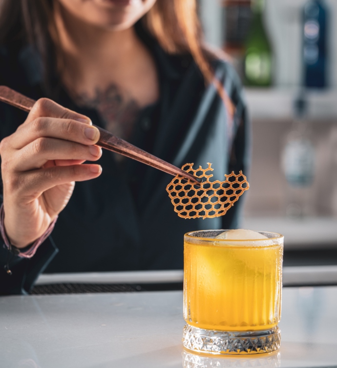 Barman ajoutant une décoration sur un cocktail orange 