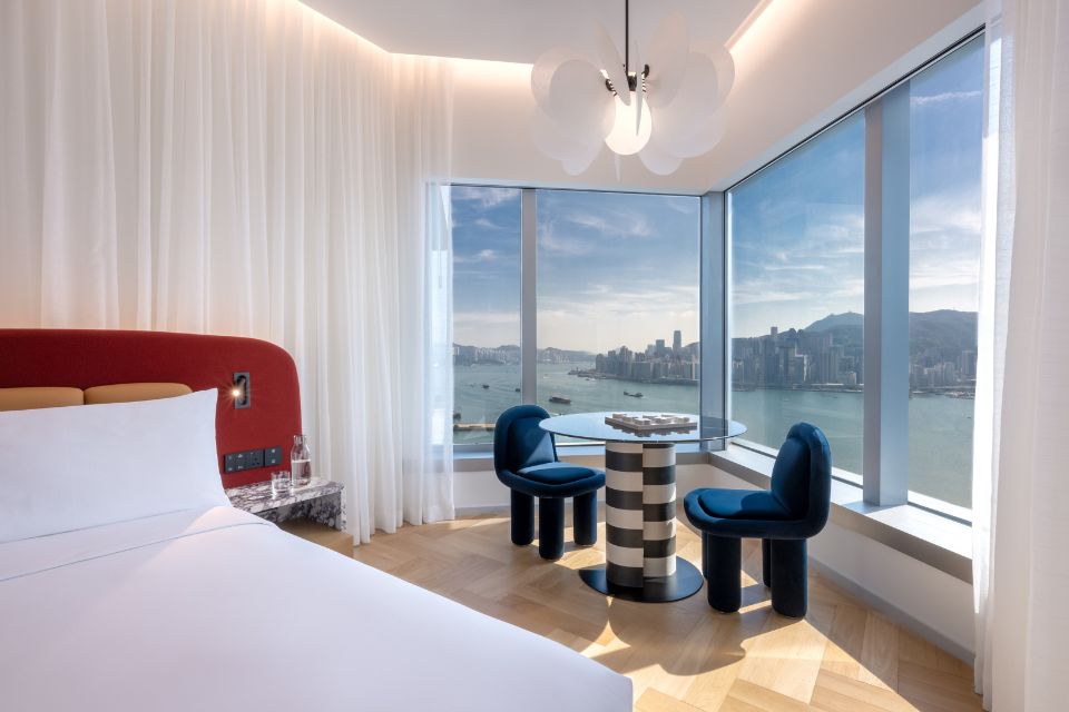 Hotel room featuring a large bed with red headboard, a table and views of the harbour