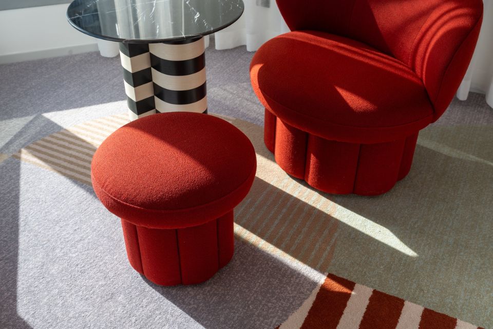 Red chair with a stool and a round black marble table with white and black striped base