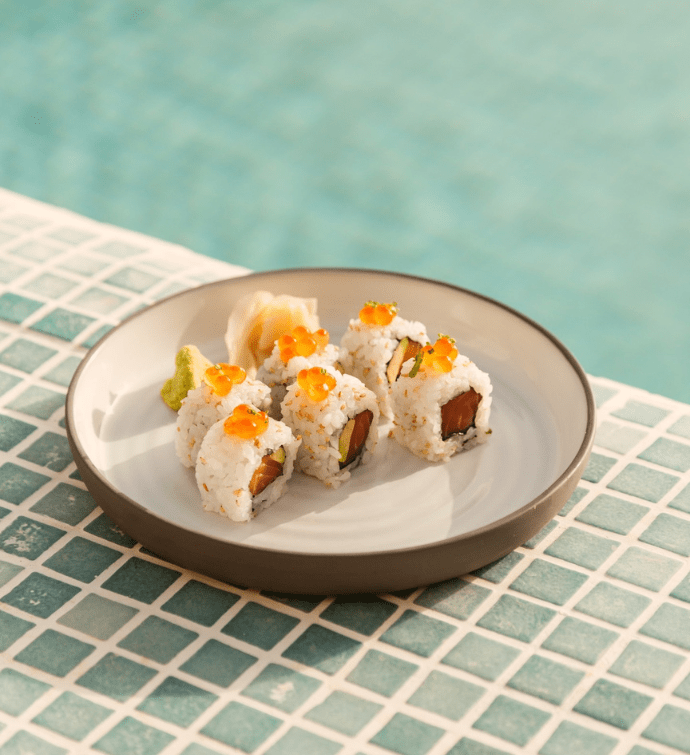 a plate of colorful sushi sitting on blue tiles next to the pool