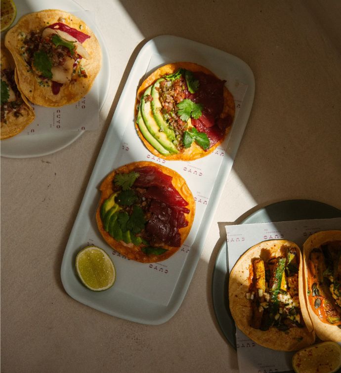 Various plates of tacos on a light tabletop