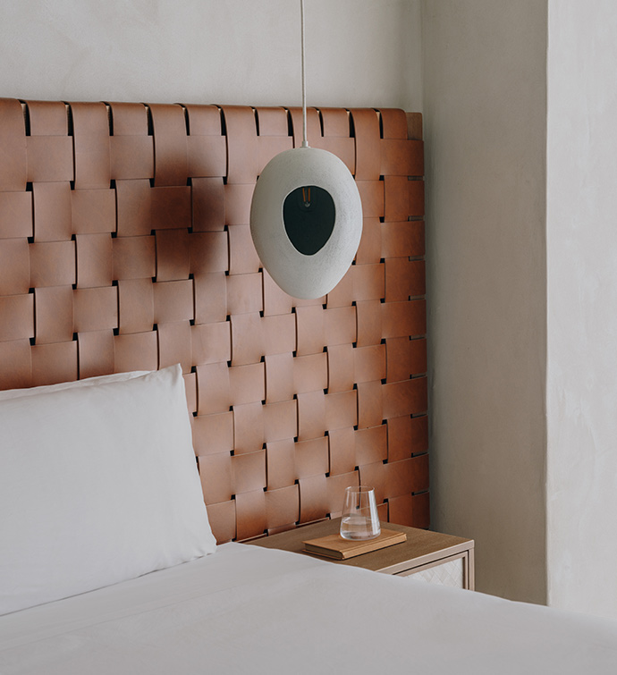 A neatly made bed with white sheets and a lamp placed on it.