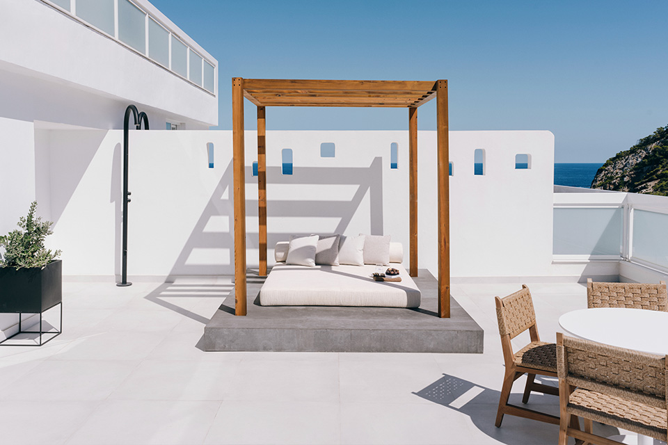 White patio with wooden daybed and table.