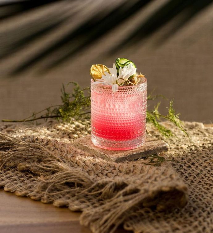 Red cocktail with fruit and flower garnish