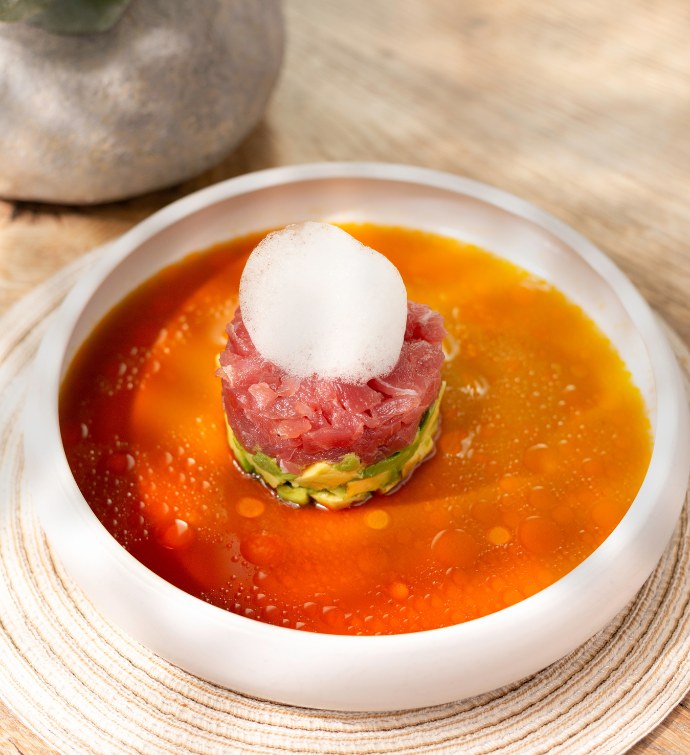 Tuna timbale dish with raw tuna in an orange sauce with foam on top