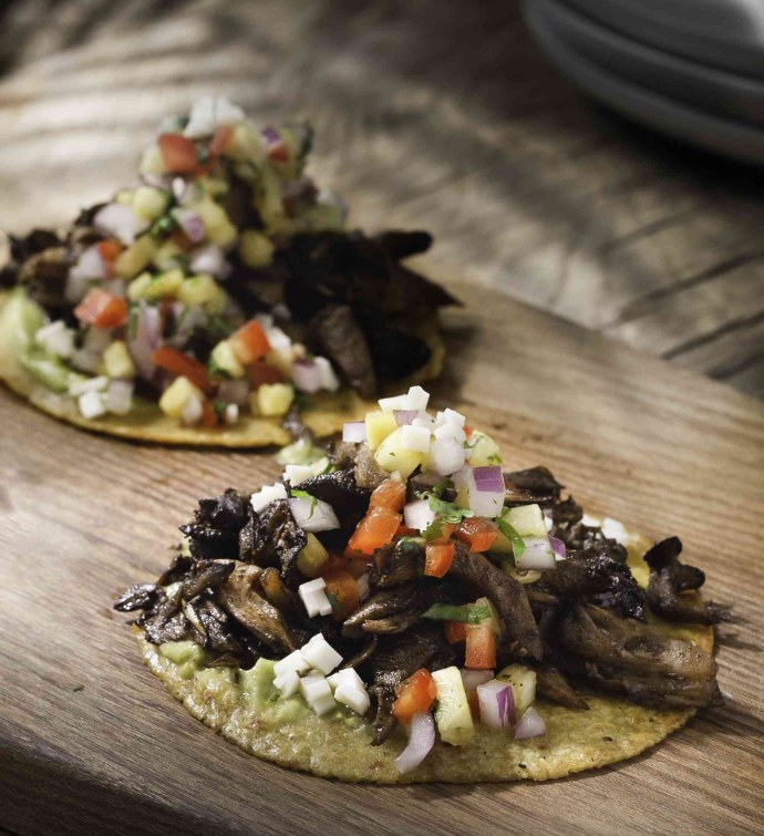 Two wild mushroom tacos garnished with tomatoes, pineapple and onion