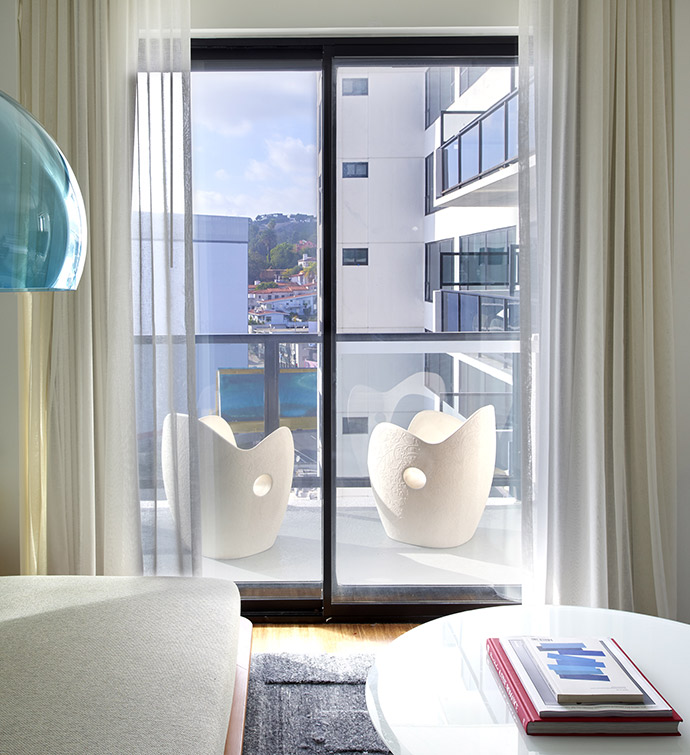 Bedroom with bed and window overlooking city skyline.