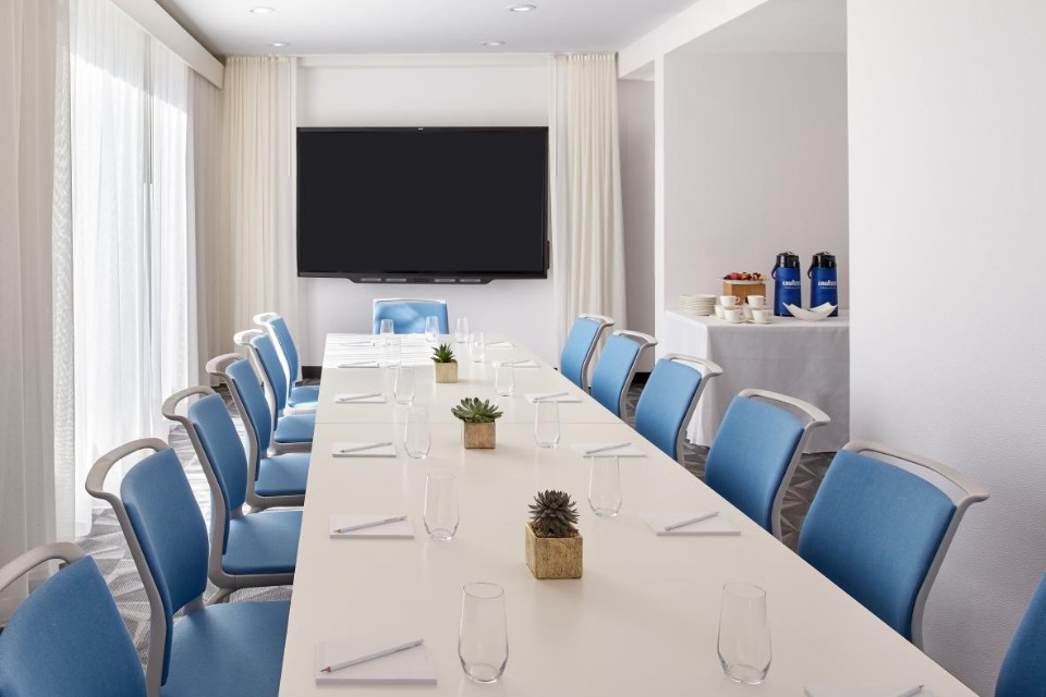 Conference room at Mondrian Los Angeles with a long table, blue chairs and a TV