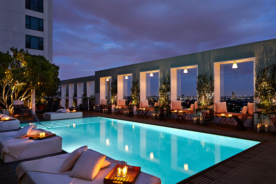 Imagen nocturna de la piscina de la azotea de Skybar LA, iluminada con velas.