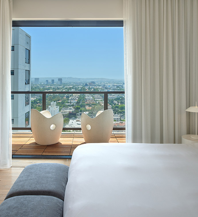 Bedroom with bed and window overlooking city skyline.