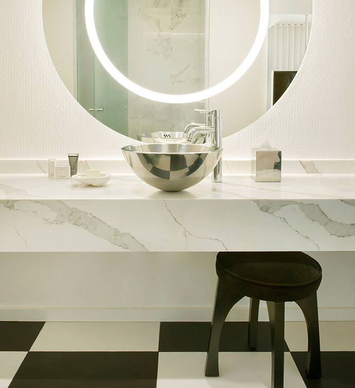 Un cuarto de baño en blanco y negro con un espejo redondo y un lavabo.