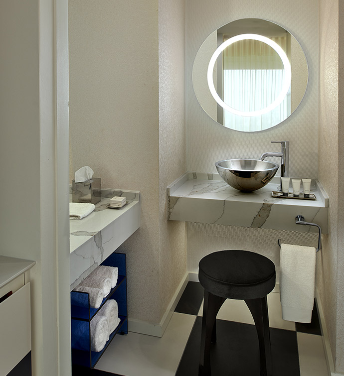 A bathroom with a sink, mirror, and a stool.