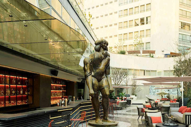 Large statue of a male figure in front of amodern building