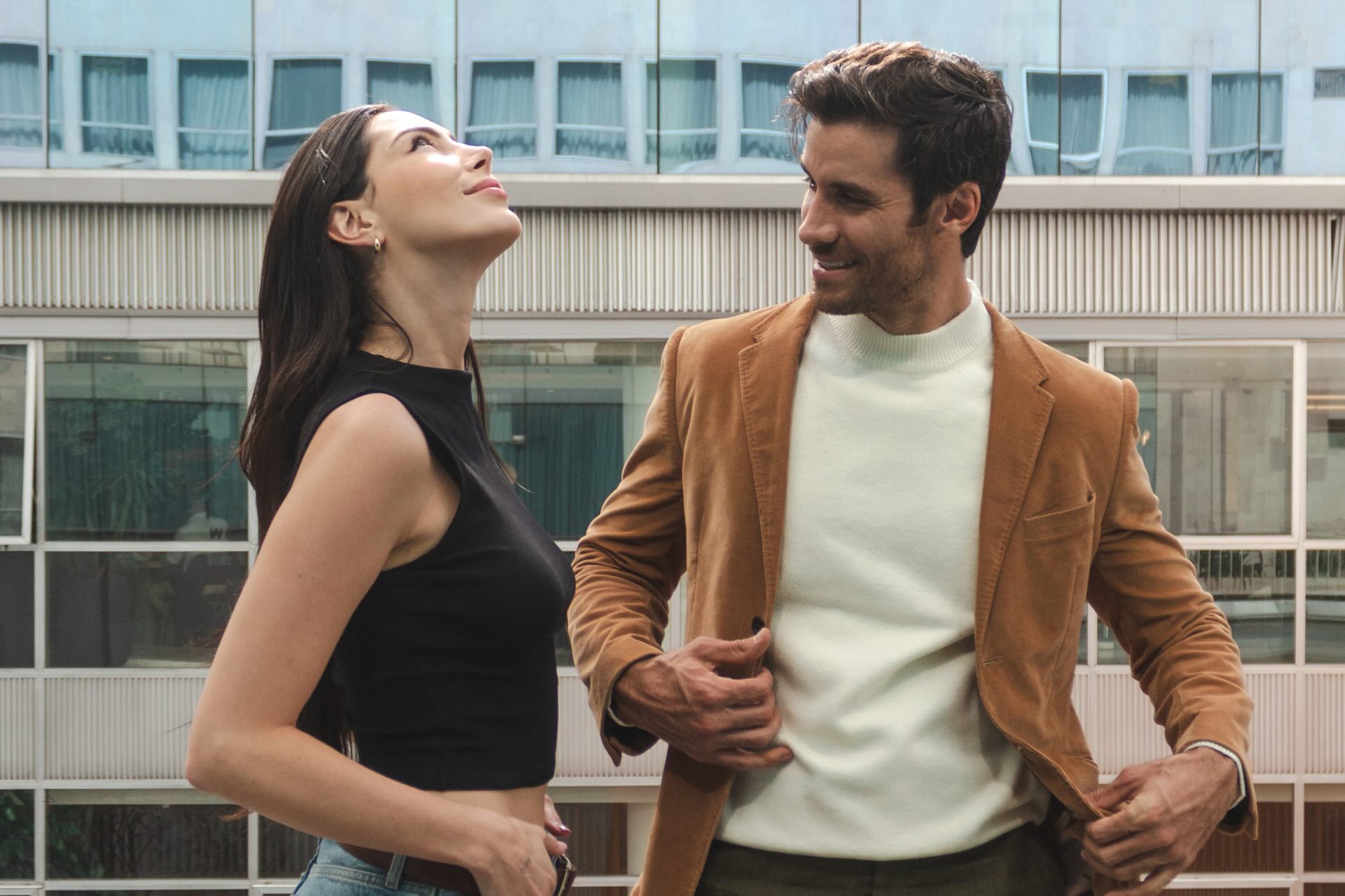 a couple standing on a terrace in fashionable clothing