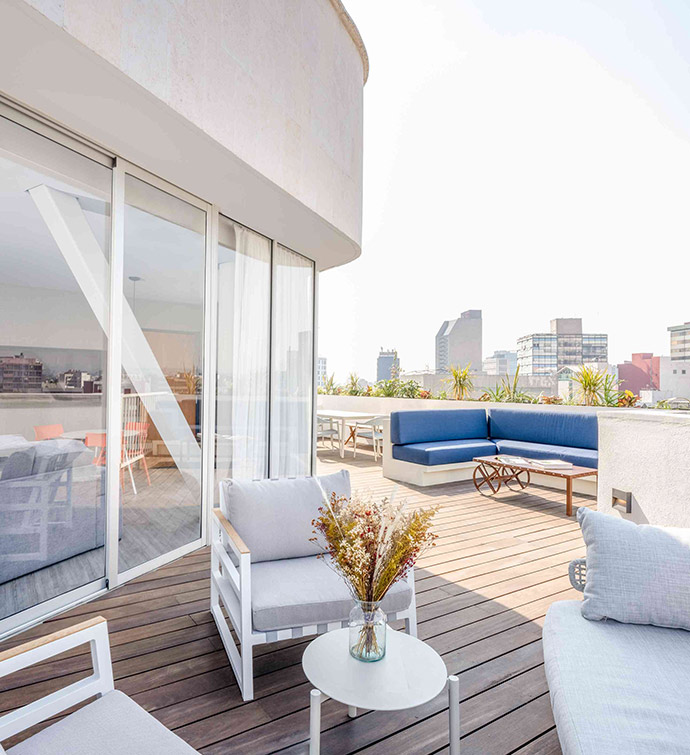 A balcony overlooking the city with white furniture.