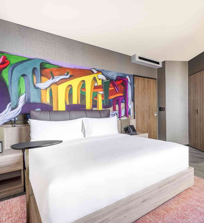 A hotel room with a captivating painting adorning the wall.