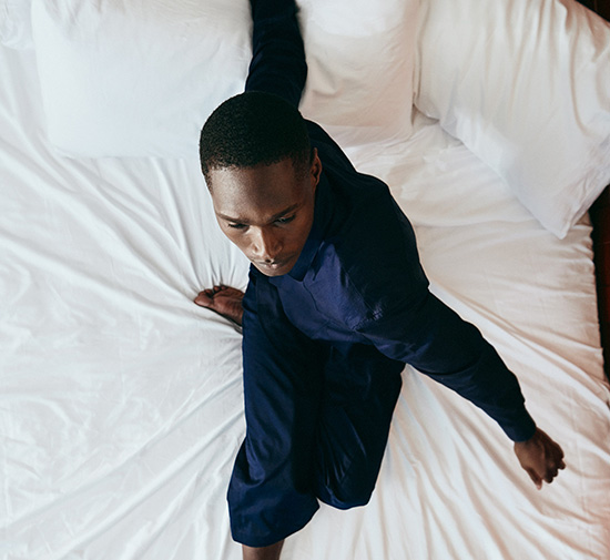 Homme en costume bleu assis sur un lit.