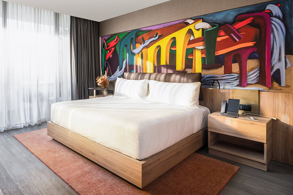 A hotel room with a captivating painting adorning the wall.