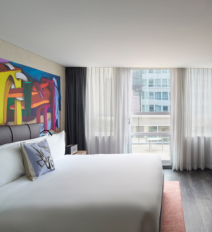 A hotel room featuring a spacious bed and vibrant artwork on the walls.