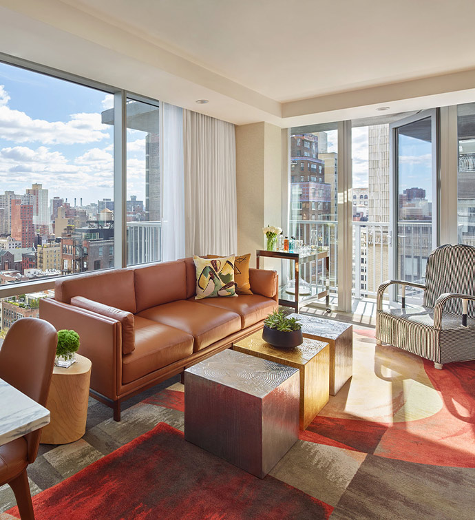 A modern living space with a leather couch and floor-to-ceiling windows showcasing a stunning cityscape.