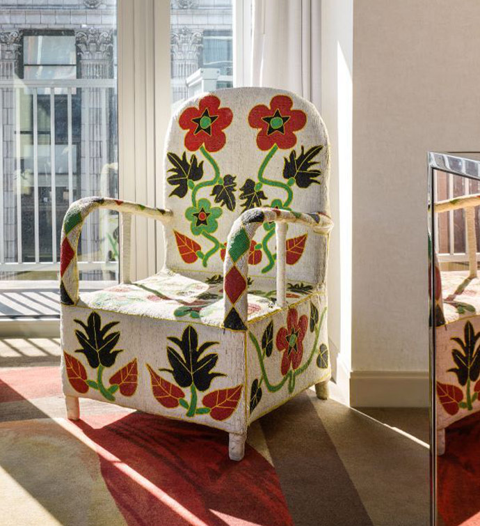 A floral-patterned chair placed in front of a window.