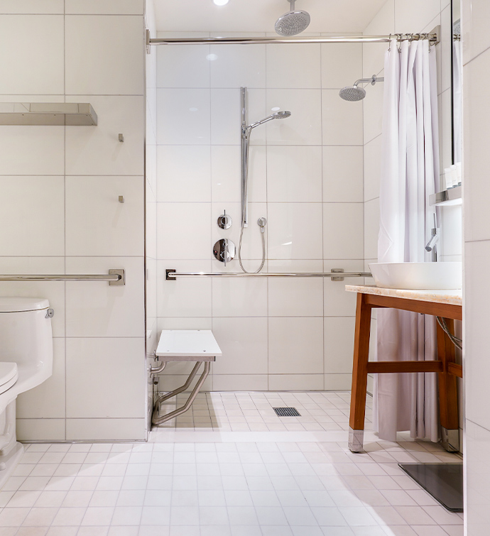 A modern accessible bathroom with a toilet, sink, and shower.