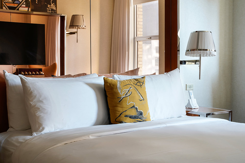 A bed with a yellow pillow on it and a lamp on the wall.