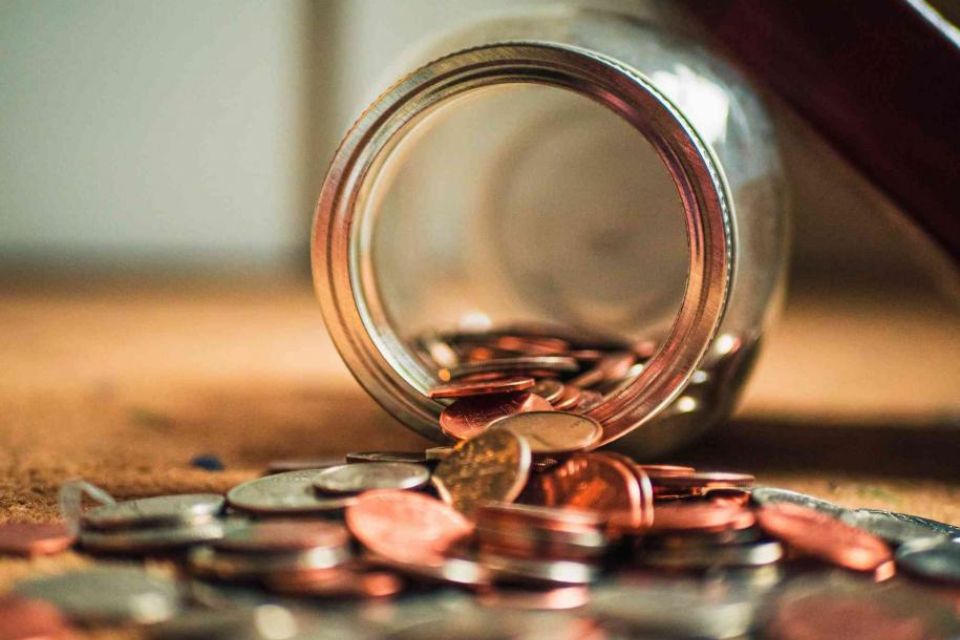 A coin jar with coins coming out of it