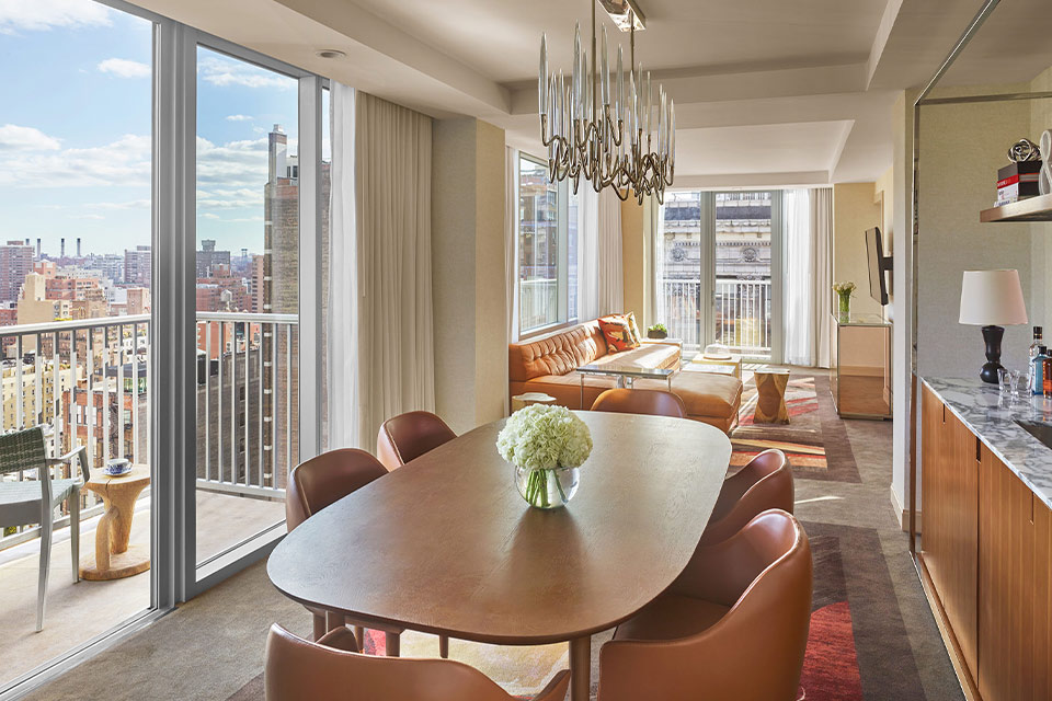 A modern living area with a table and chairs, overlooking the city skyline.