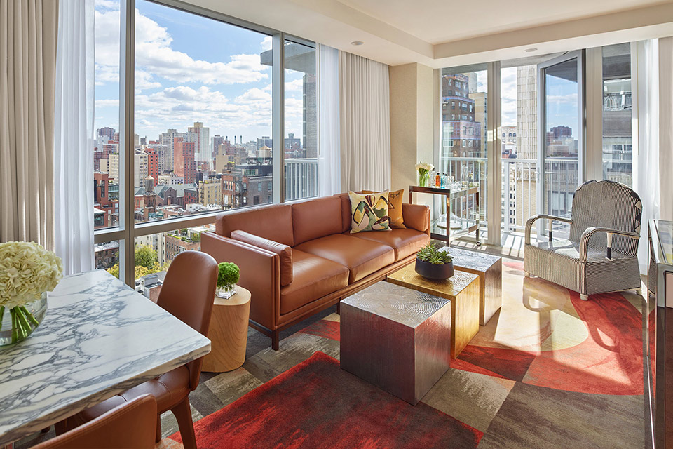 A modern living space with a leather couch and floor-to-ceiling windows showcasing a stunning cityscape.