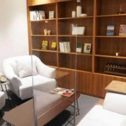 a seating area with wood shelved and white chairs 