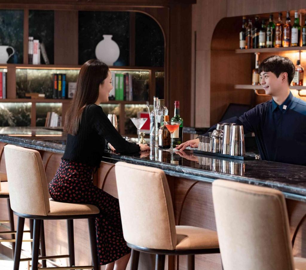 Bartender passes a woman patron a drink in a modern looking bar