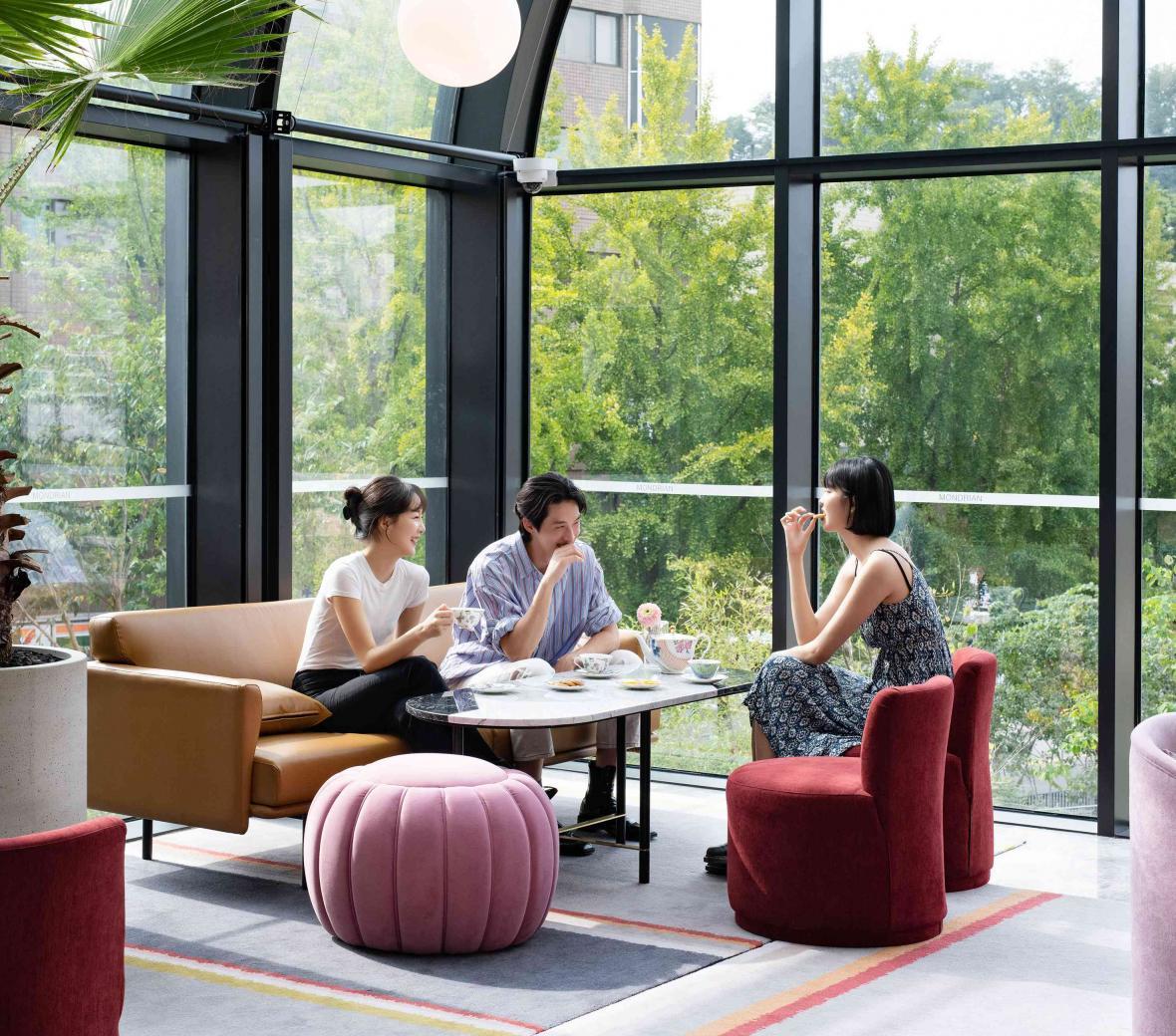 Two women and one man sit at a table in lounge chairs laughing