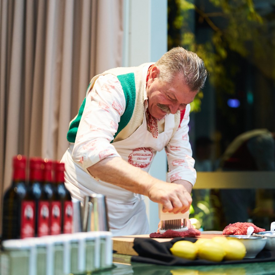 Male chef leaning over a table making beef tartare