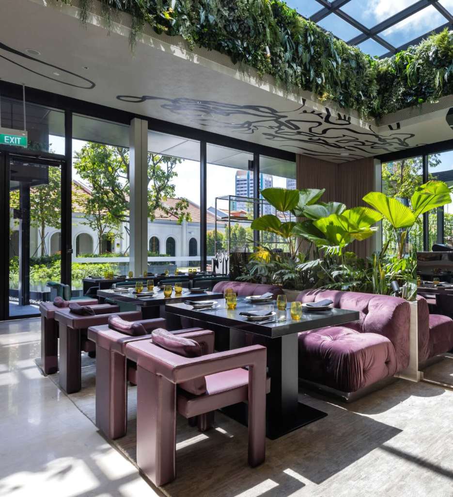 Interior of Bottega di Carna restaurant with plush, purple seating, tables and a skylight with plants